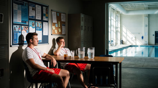 Shaded aquatics staff break area with off-duty guards relaxing beside a pool