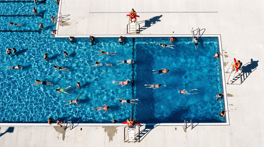 Overhead view of a busy public pool with three lifeguards covering separate zones