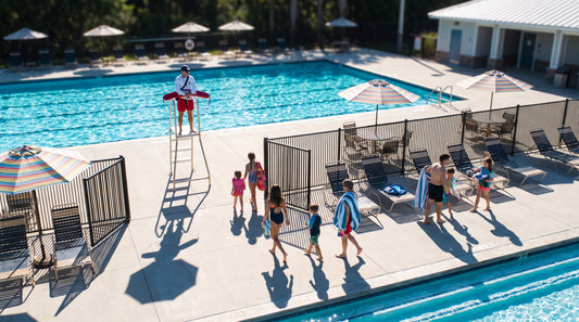 Opening day at a community pool with families arriving and a lifeguard on the stand