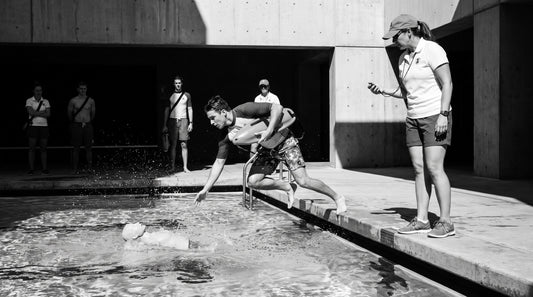 Guard team running a timed rescue drill with a training manikin while a supervisor observes