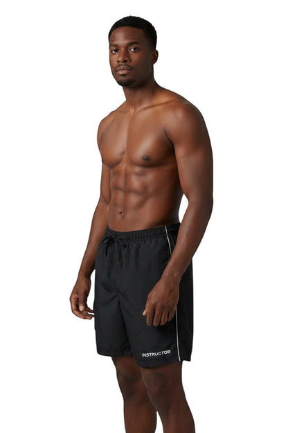 The Lifeguard Store black polyester board shorts with liner, elastic waistband, drawstring, and "INSTRUCTOR" text.