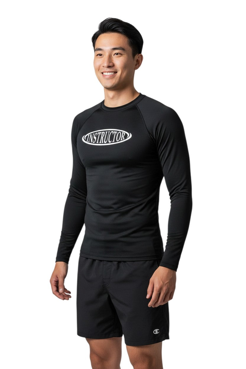 The Lifeguard Store black long sleeve rashguard with white "INSTRUCTOR" graphic on chest. Polyester-spandex blend.