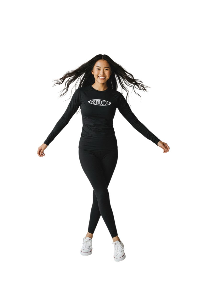 The Lifeguard Store black long sleeve crew neck rashguard with white "INSTRUCTOR" graphic on chest. Made of polyester and spandex.