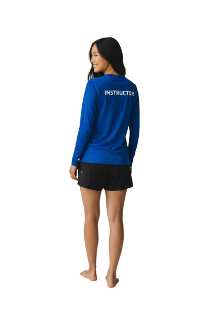 The Lifeguard Store blue long sleeve rashguard with white "INSTRUCTOR" text on back. Polyester-spandex blend with UPF50+ protection.
