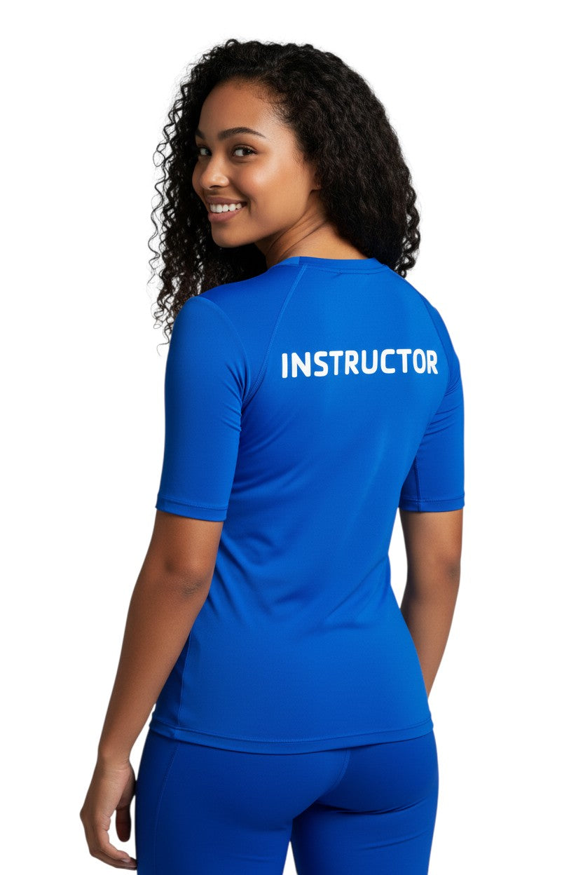The Lifeguard Store blue short-sleeve rashguard with white "INSTRUCTOR" text on back. Made of polyester and spandex.
