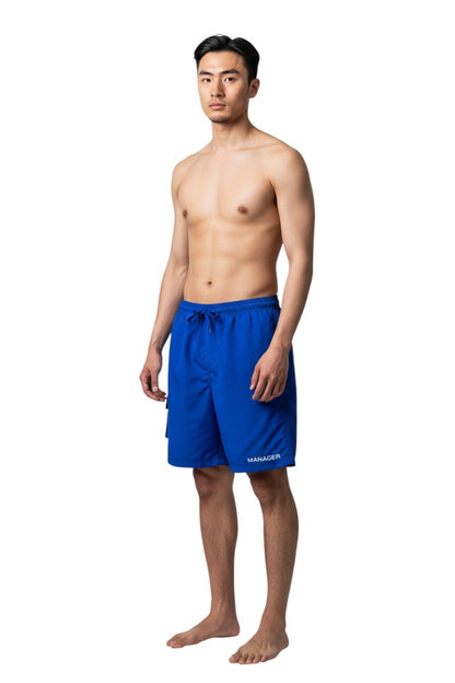 The Lifeguard Store blue polyester board shorts with liner, elastic waistband, drawstring, and cargo pocket. "MANAGER" printed on leg.