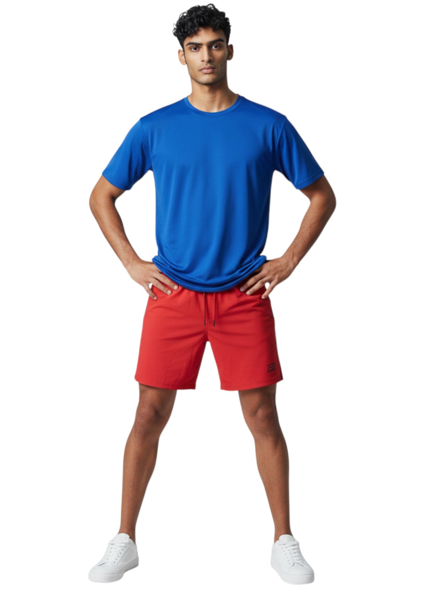 Male model wearing The Lifeguard Store blue short sleeve crew neck rashguard with red shorts and white sneakers.