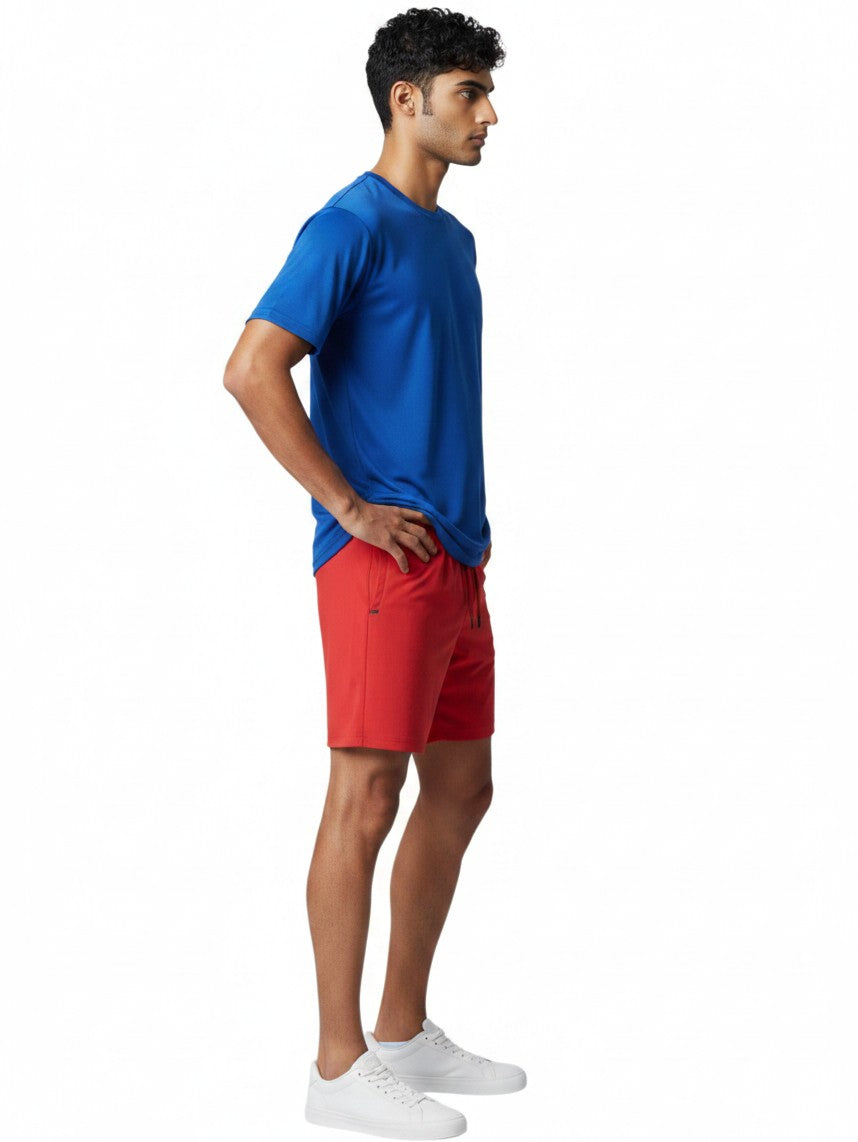 Male model wearing The Lifeguard Store blue short sleeve crew neck rashguard and red shorts in profile view