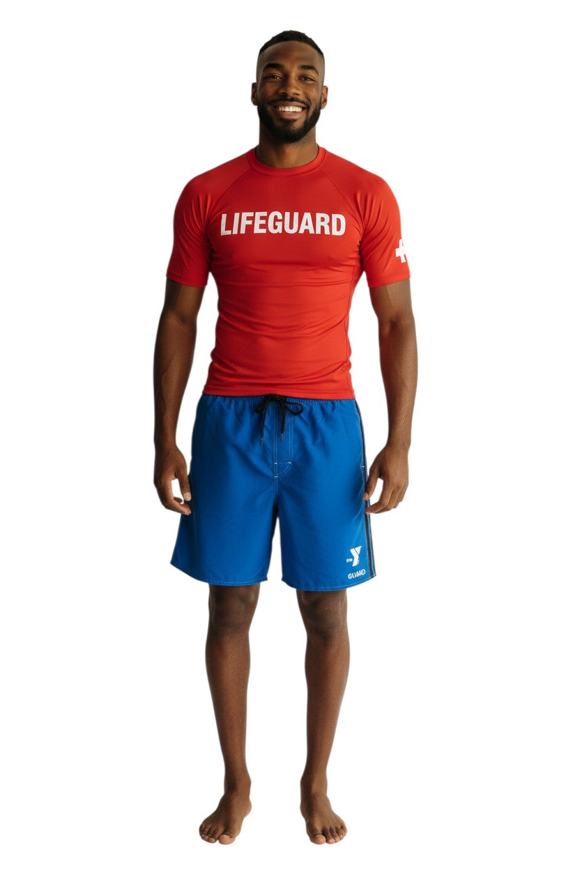 The Lifeguard Store blue polyester board shorts with black side stripes and YMCA Guard logo. Elastic waistband, drawstring, and side pocket.