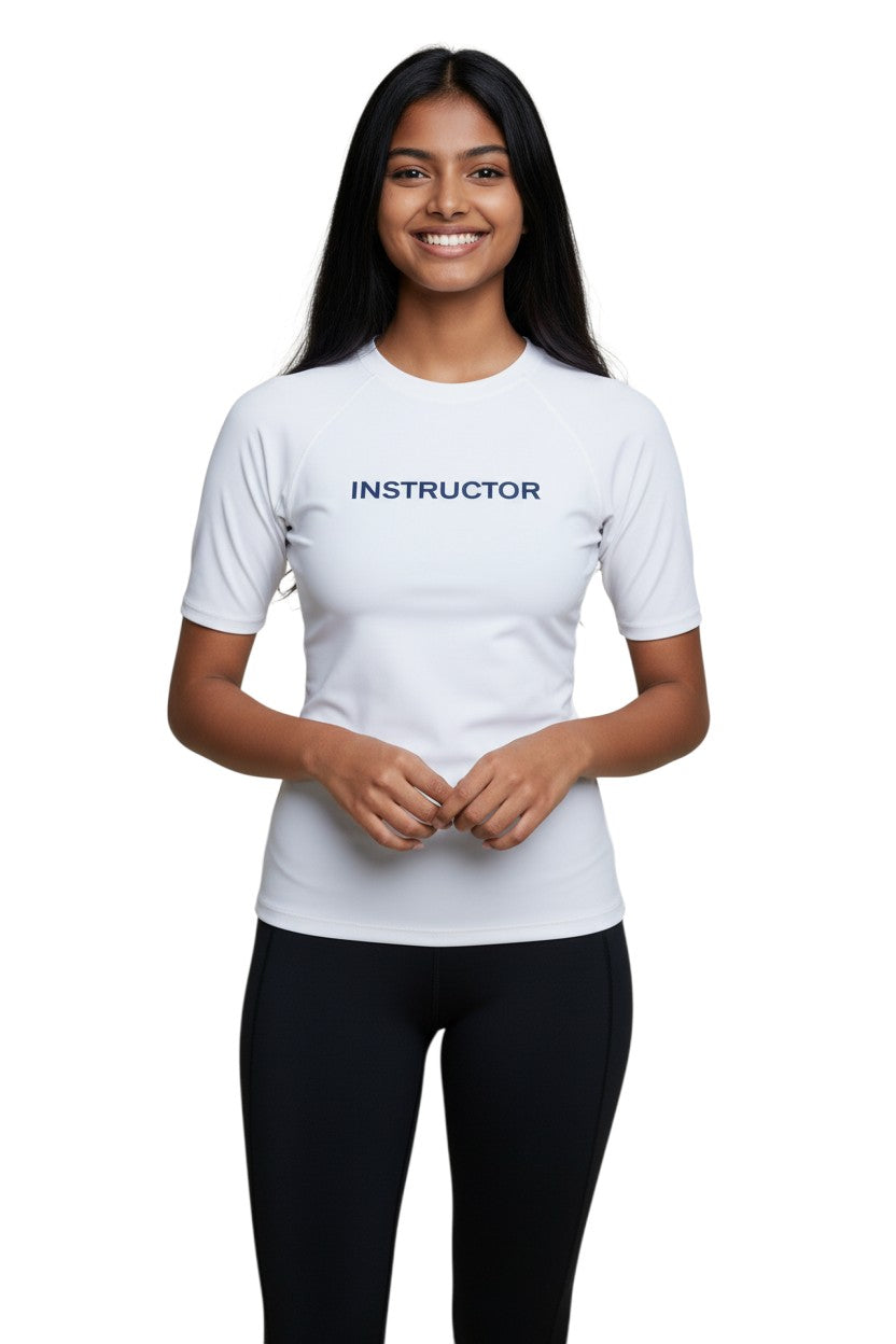 The Lifeguard Store white short sleeve rashguard with "INSTRUCTOR" printed in navy blue on the chest. Made of polyester and spandex.