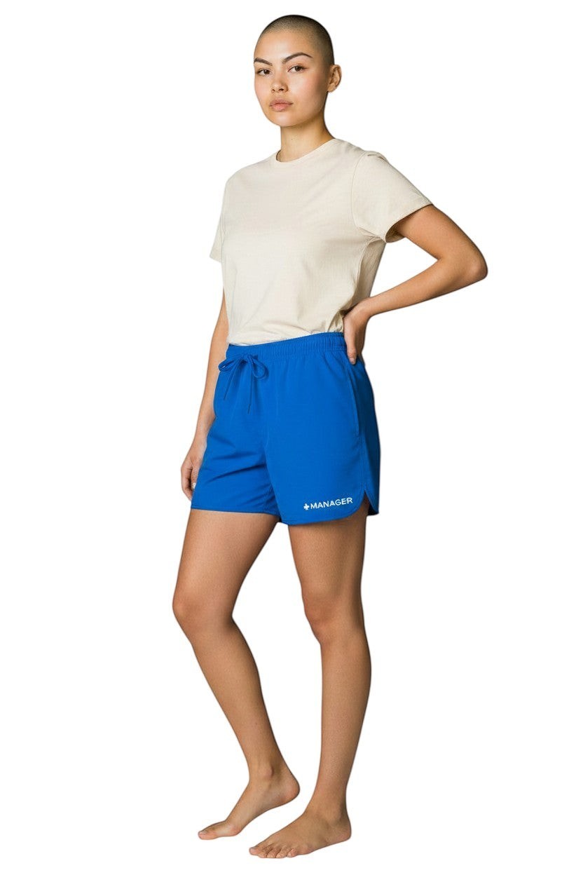 The Lifeguard Store Kiefer Manager women's royal blue 5" polyester shorts with drawstring waist and white "+MANAGER" logo.