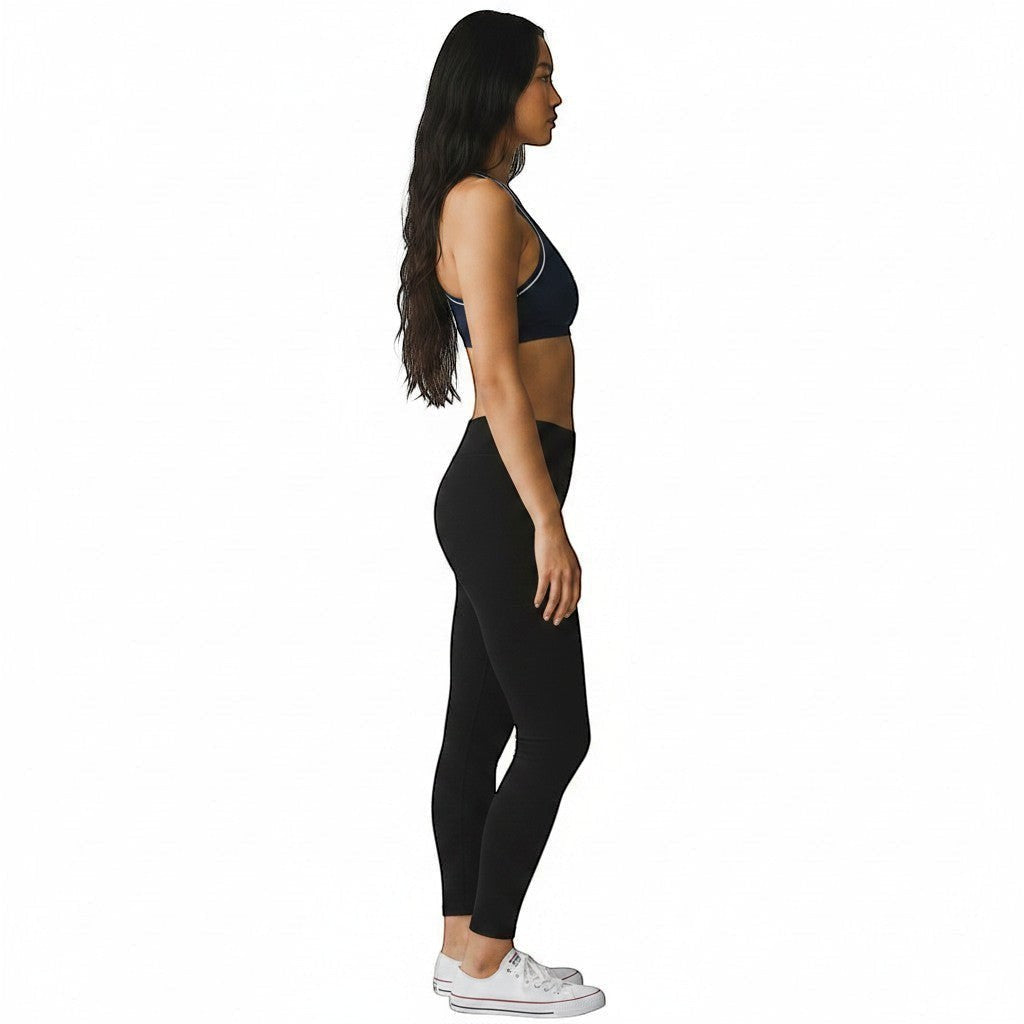 The Lifeguard Store Kiefer reversible racer back top in navy blue worn by a model with black leggings and white sneakers.