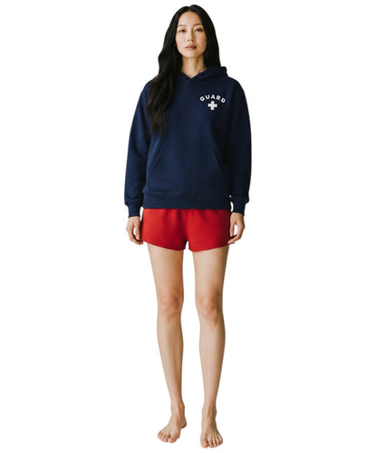 The Lifeguard Store navy blue hooded sweatshirt with white GUARD logo worn by a woman with red shorts