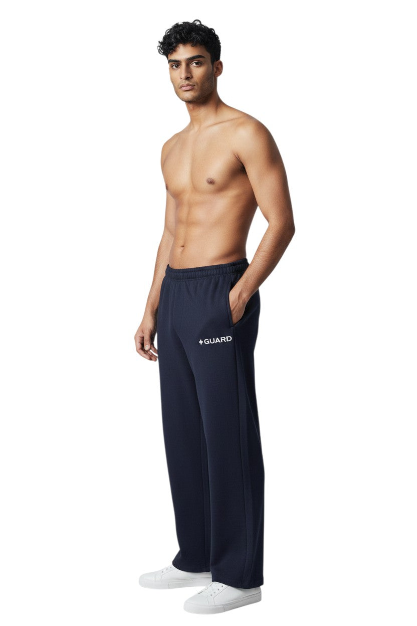 The Lifeguard Store navy blue sweatpants with drawstring and side pockets, featuring a white '+ GUARD' logo on the left thigh. Made of 50% Cotton/50% Polyester.