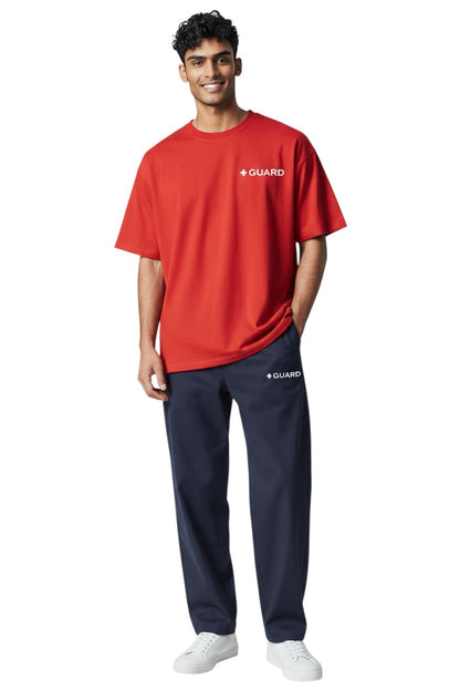The Lifeguard Store navy blue sweatpants with drawstring and side pockets, featuring a white '+ GUARD' logo on the left thigh. Made of 50% Cotton / 50% Polyester.