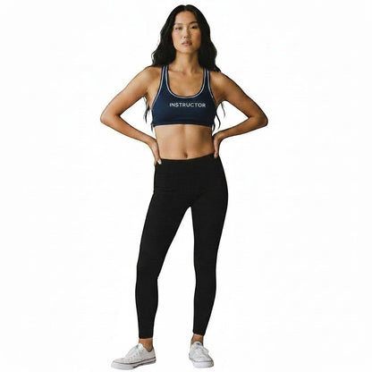 The Lifeguard Store navy blue reversible racer back instructor top worn by a model with black leggings.