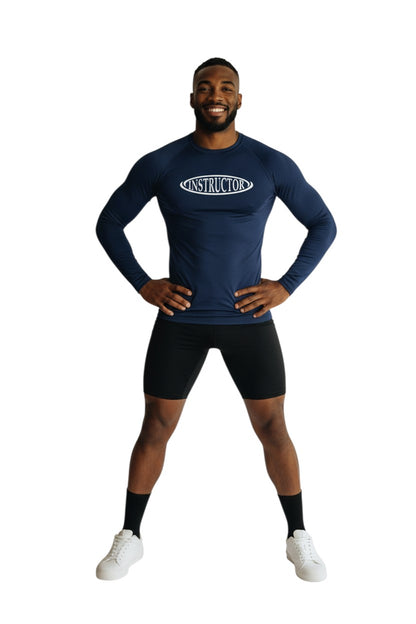 The Lifeguard Store navy blue long sleeve rashguard with white "INSTRUCTOR" graphic on chest. UPF50+ protection.