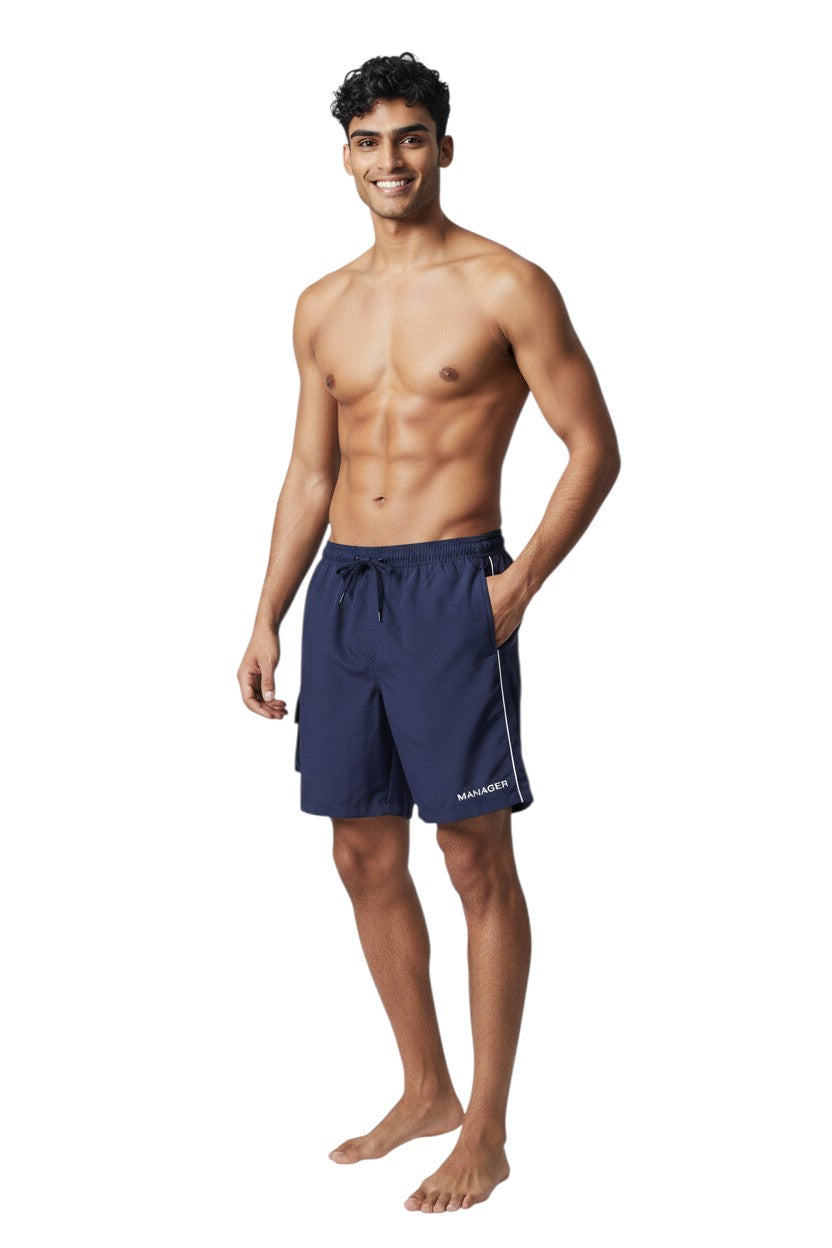 The Lifeguard Store navy blue polyester board shorts with liner, elastic waistband, drawstring, cargo pocket, and "MANAGER" text.