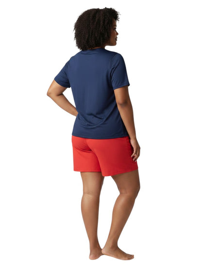 A model wearing The Lifeguard Store navy blue short sleeve crew neck rashguard and red shorts, back view.
