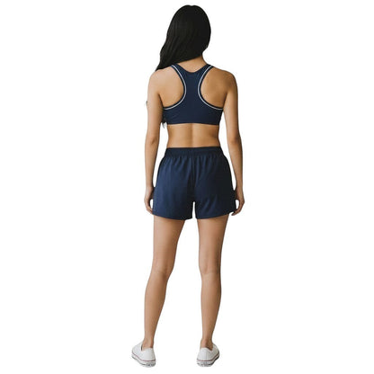 The Lifeguard Store navy blue reversible racer back guard top with white trim worn by a woman from the back view.