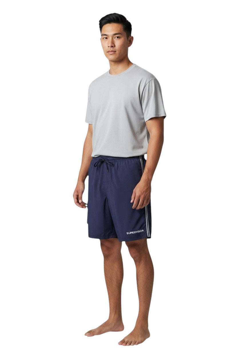 The Lifeguard Store navy blue polyester board shorts with liner, elastic waistband, drawstring, and cargo pocket. Features "SUPERVISOR" text.