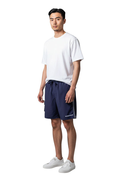 The Lifeguard Store navy blue polyester board shorts with liner, elastic waistband, drawstring, cargo pocket, and "SUPERVISOR" text.