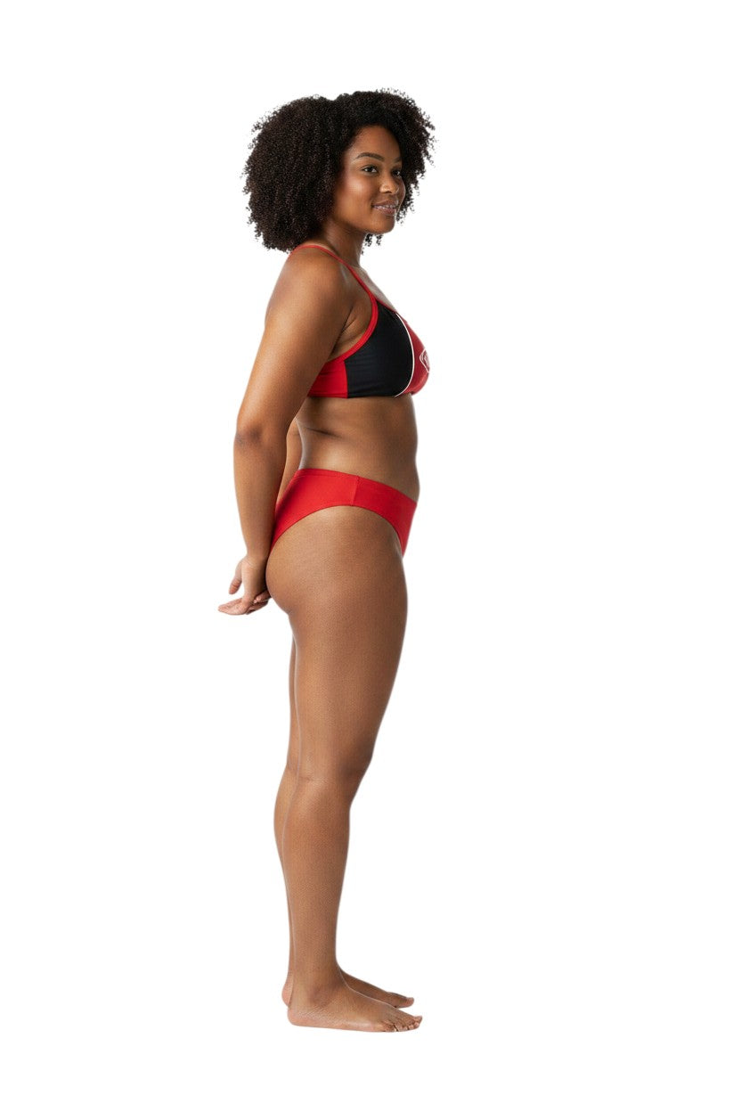 Model wearing The Lifeguard Store RISE Guard Poly Splice Bikini in red and black, side view.