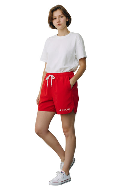 The Lifeguard Store red polyester 5" inseam shorts with elastic waistband, drawstring, and "+ STAFF" graphic.