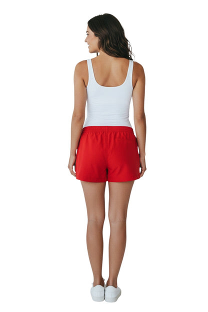 The Lifeguard Store red polyester shorts with elastic waistband, drawstring, and YMCA instructor logo. Quick-dry fabric.