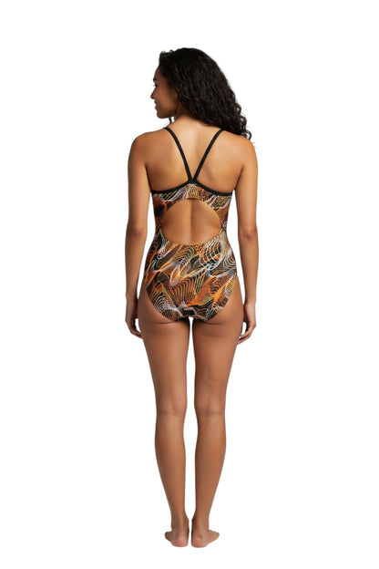 The Lifeguard Store RISE Sandies Female Helix Poly Swimsuit with orange, white, and yellow abstract wavy lines on black background. Features H-back straps and open back.