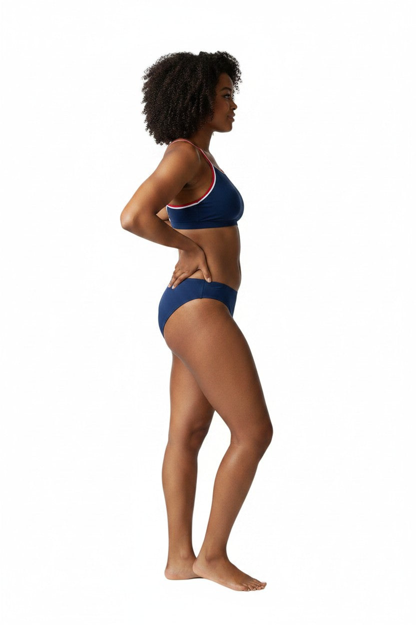 The Lifeguard Store tri-color athletic bikini in navy, white, and red worn by a model in a side profile view.