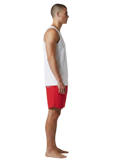 The Lifeguard Store white cotton staff tank top worn by a male model in profile view with red shorts
