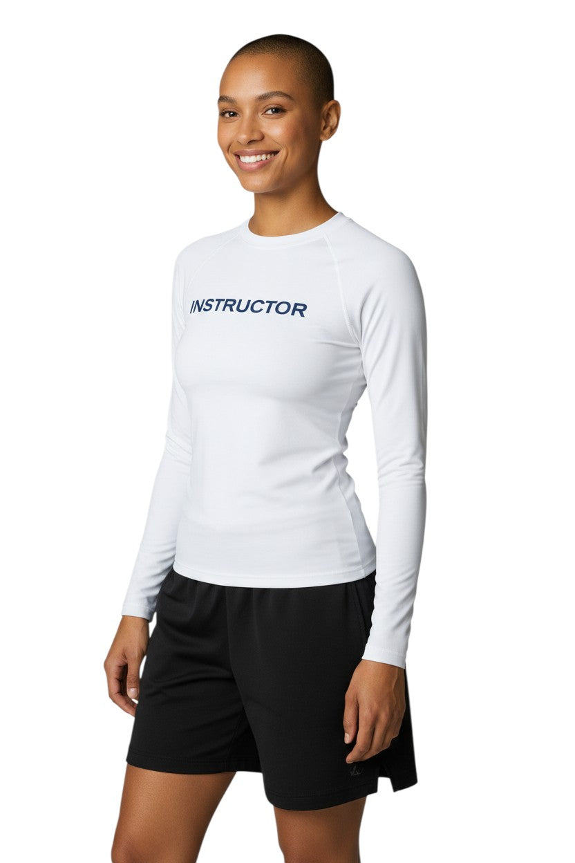 The Lifeguard Store white long sleeve rashguard with "INSTRUCTOR" printed in navy blue on the chest. Made of poly stretch fabric.