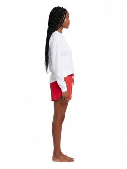 The Lifeguard Store white long sleeve Dri-Fit guard shirt worn by a model in profile view with red shorts
