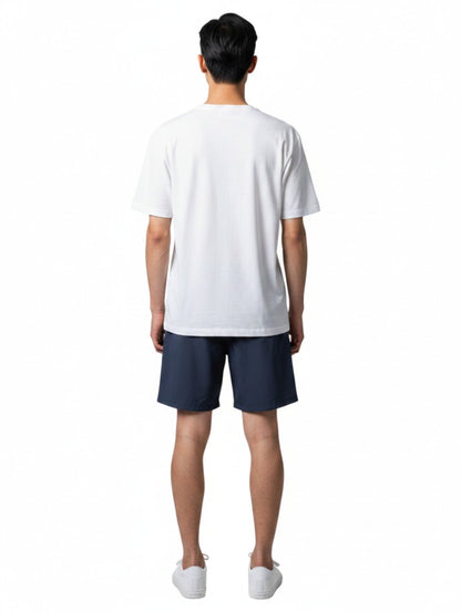 Back view of a man wearing The Lifeguard Store white short sleeve crew neck rashguard with navy blue shorts