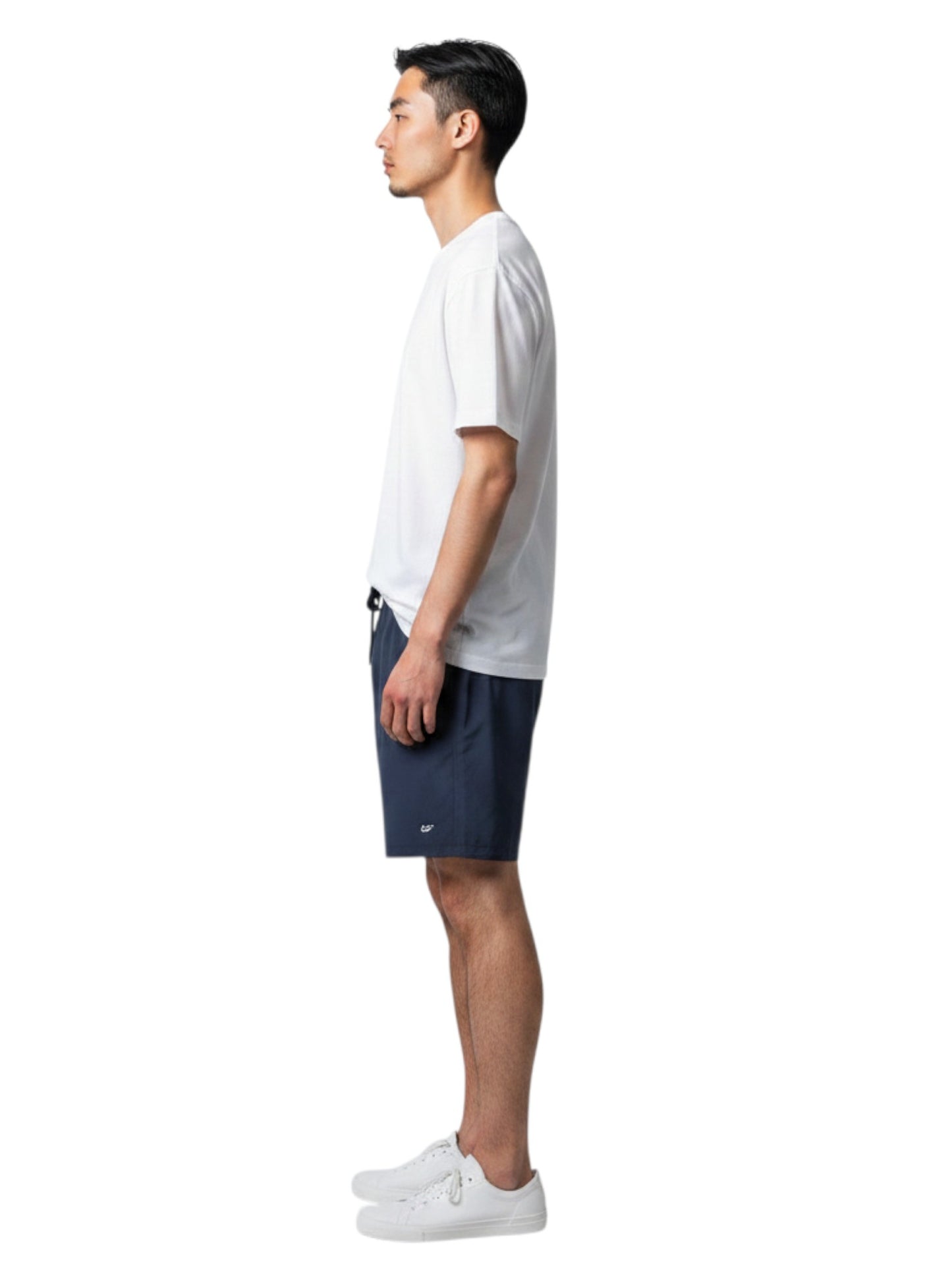 Male lifeguard wearing The Lifeguard Store white short sleeve crew neck rashguard and navy shorts, side view.