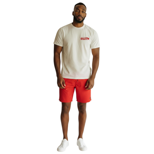 The Lifeguard Store white cotton Staff Tee with red logo worn by a male model with red shorts and white sneakers