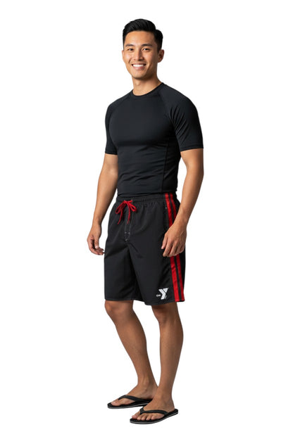 The Lifeguard Store black polyester board shorts with red side stripes and YMCA logo. Elastic waistband with drawstring.