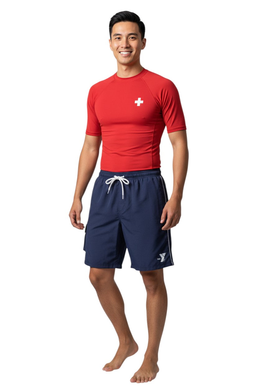 The Lifeguard Store navy blue YMCA board shorts with drawstring waist, cargo pocket, and white YMCA logo.